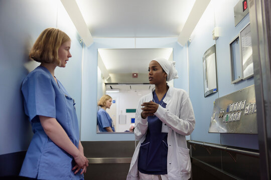 Female doctors taking to each other inside lift in hospital