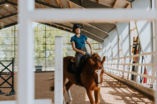 View of female horse rider using indoor riding paddock
