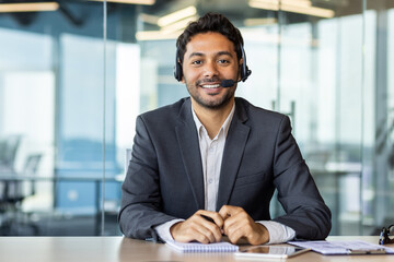 Portrait of young successful arab businessman, man with headset phone for video call smiling and...