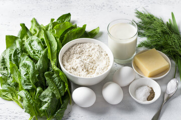Ingredients: spinach, sorrel, flour, eggs, yogurt, cheese, spices, baking powder and greens for cooking a delicious vegetarian pie or cupcake on a light blue background, top view - 637896037
