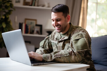 Patriotic male soldier video chatting with his family on a laptop