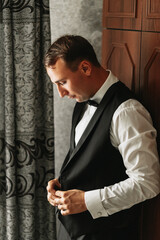 Preparation for the morning of the bride and groom. portrait photo of an elegant man getting dressed for a wedding celebration. The groom, dressed in a white shirt and bow tie