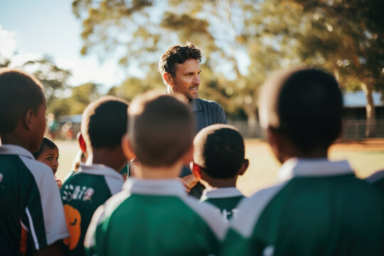 Coach having a team talk with children in a school ground