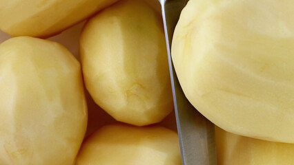 peeled potatoes and a knife on the cutting board