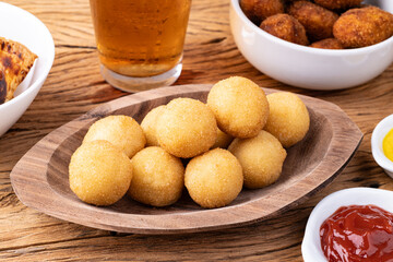 Typical brazilian snack cheese ball on a plate with soda glass, ketchup and mustard