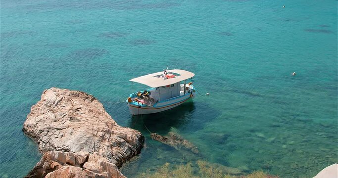 Fishing boat by itself in a aqua coloured greek bay