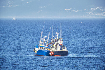 Commercial fishing boat in Atlantic ocean, two ships trading and cargo fishing