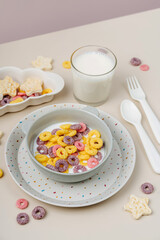 Colorful cereal rings with milk in bowl. Dry children's breakfast. Cute children's plates and bowls with tasty food. Creative serving for baby. Concept of kids menu, nutrition and feeding.