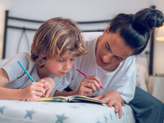 Teen boy drawing in notebook with mother