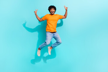 Full body portrait of handsome excited person jumping demonstrate v-sign empty space isolated on turquoise color background