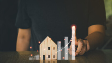 Real estate investment concept. Businessmen pointing finger on virtual graph and wooden house model, real estate growth in the future, finance, banking, lending, and trading.