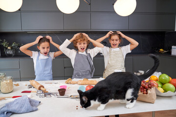 Shocked children looking at cat on table