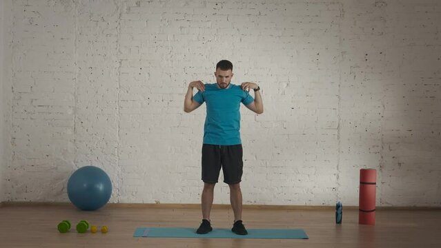 Man fitness instructor in sportswear doing an upper body warm up for online class at his home studio.