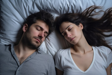 Fototapeta na wymiar Top down view of a caucasian couple sleeping in a white sheet bed