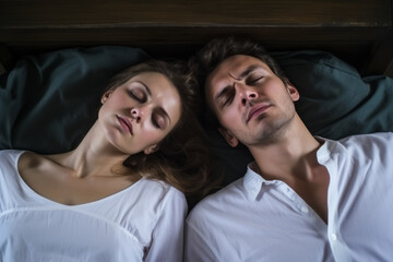 Top down view of a caucasian couple sleeping in a white sheet bed