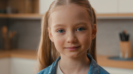 Moving shot close up little schoolgirl Caucasian child girl smiling looking at camera portrait at home kitchen cute 10s daughter adopted custody kid baby childcare health pediatric family childhood