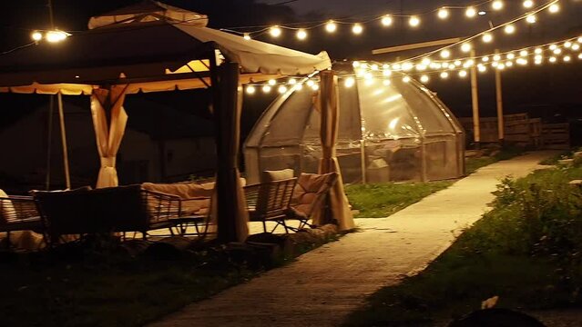 A mountain hotel courtyard with night lights and gazebos on a cozy late evening