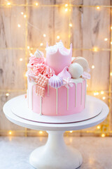 Princess pink cake with fondant crown, cotton candy, macarons, popsicles and ake pops on festive background