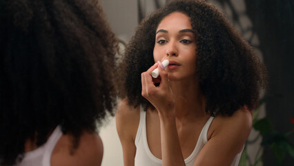 Beautiful African American woman looking in mirror reflection morning beauty routine preparation...