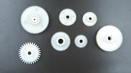 white plastic gears on a dark background. connection mechanism details. subject of movement