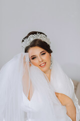Portrait of a bride with a beautiful hairstyle and tiara on her head and natural makeup posing in a...