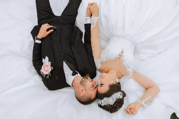 beautiful fairy tale happy bride and stylish groom lying on the grass on their wedding day