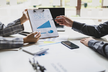 Meeting with business partners to discuss financial advisors to analyze market growth charts in business reports and plan investment strategies.