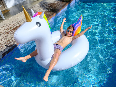 Content kid lying on inflatable ring and floating in swimming po - Powered by Adobe