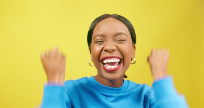 Excited woman cheers, winning happy dance, yellow studio background