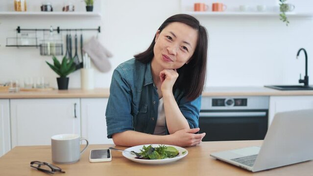 Remote employee sitting at table with laptop and salad