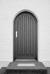 Dark door with a round arch on a light wall.