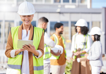 Tablet, architecture and a senior woman construction worker on a building site with her team in the...
