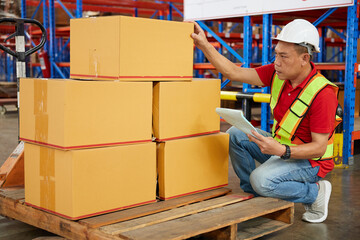 factory worker or warehouser checking corrugated boxes in the warehouse storage