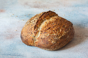 Fresh whole grain sourdough bread with flax seeds, oatmeal, sesame seeds on colored background, healthy food concept unleavened bread.