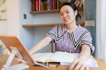 A young Chinese woman is learning on a tablet at home