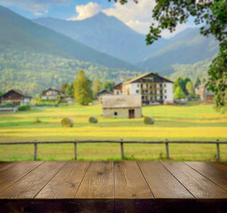 Fototapeta na wymiar An empty wooden countertop on a blurry natural background. Spring, summer, autumn background. Mountain, rural landscape. field, haystacks. A sunny day. A place to copy. A village house in the mountain