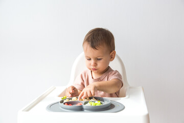 Cute little baby infant eating complementary foods on white background. space for text