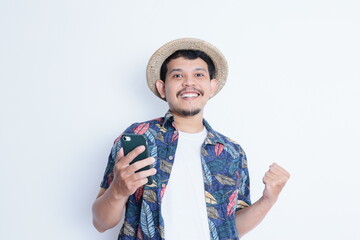 Asian man wearing beach shirt smiling happy while holding mobile phone