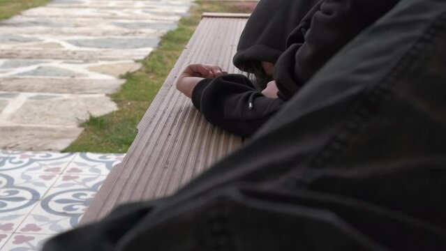 A homeless man sleeps in a public park. A runaway teenager sleeps in a park.