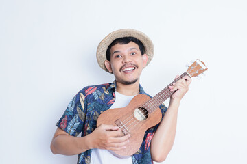a young man in a beach suit holding a ukulele and smiling at the camera. vacation and traveling concept