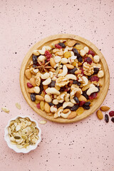 Aesthetic assorted nuts in wooden bowl. Healthy food and snacks. Walnuts, almonds, hazelnuts and cashews. Raisins and cranberries