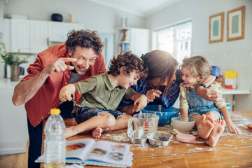 Young caucasian family being messy and having fun baking together in the kitchen