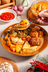 Lontong sayur or vegetable rice cake is an Indonesian traditional rice dish made of pieces of lontong served in coconut milk soup with shredded chayote, tempeh, tofu, hard-boiled egg, sambal, rendang