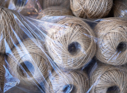 rolls of natural hemp wire for parcel twine, string, packing or diy.fencing strand,polypropylene orange, blue twine.spools in plastic bag,woman hand,market store sale concept