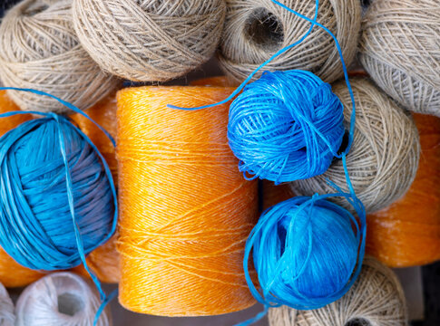 rolls of natural hemp wire for parcel twine, string, packing or diy.fencing strand,polypropylene orange, blue twine.spools in plastic bag,woman hand,market store sale concept