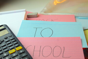 A photo of the words 'Back to School' written on coloured flashcards on a desk with calculators, rubbers and folders. 