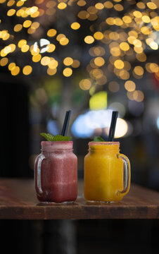 a couple of fruit smothiewith lights at the bokeh background 