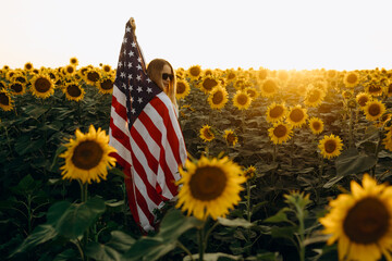 Young woman holding American flag at sunset. America celebrate 4th of July. Independence Day.