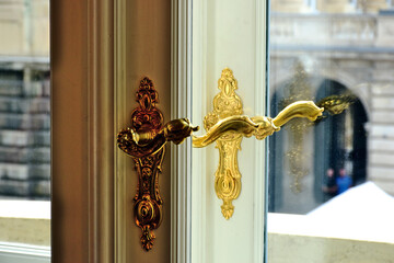 beautiful decorative shiny brass door handle closeup. ornate white wood and glass balcony door....