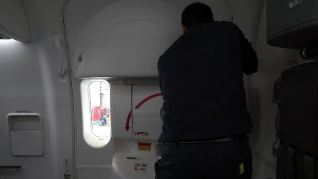 Male latino aircraft technician opening an airplane door from the inside.